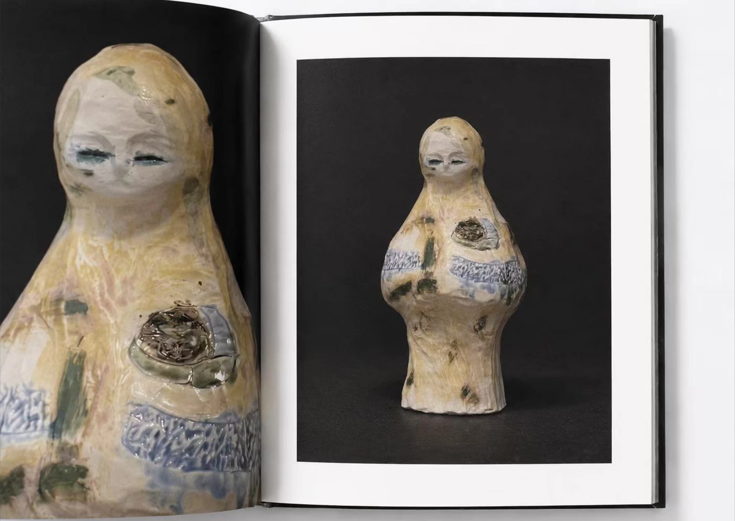 An open portfolio showing a pale ceramic figure and a close-up of its face and torso.