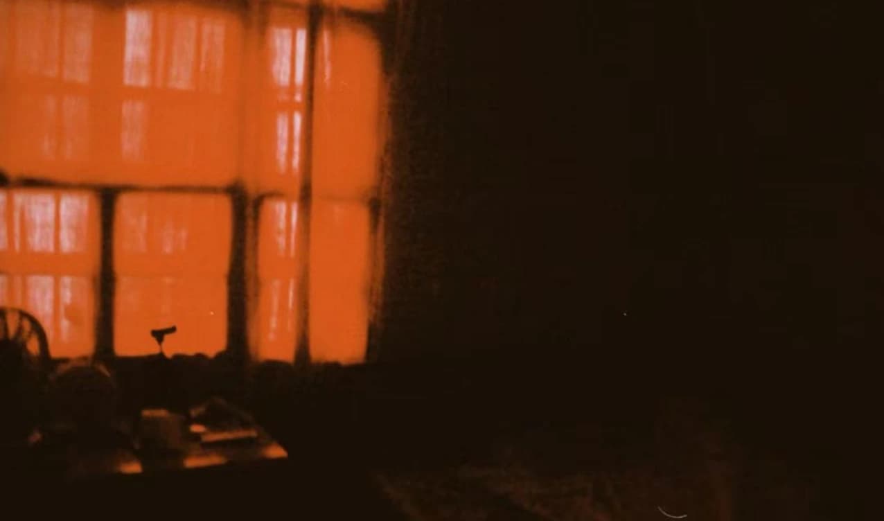 An orange-lit window in a dark room.