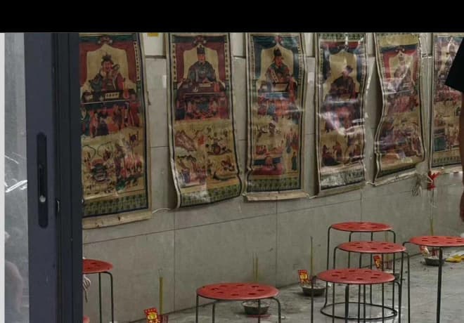 Small red stools in front of colorful hanging pictures.
