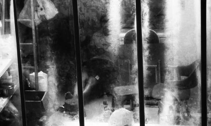 Smoke rising behind vertical bars, in black and white.