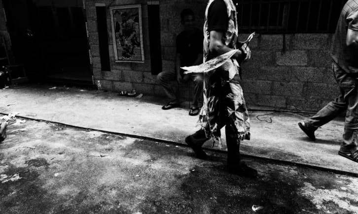 A person walking along a sunlit street, in black and white.