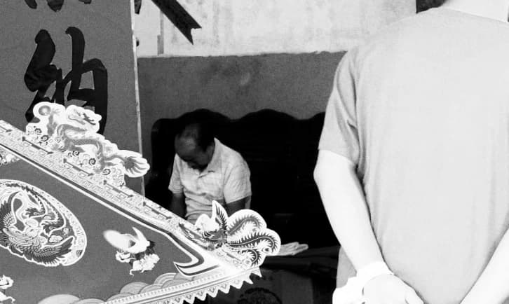 People beside a decorated surface, in black and white.