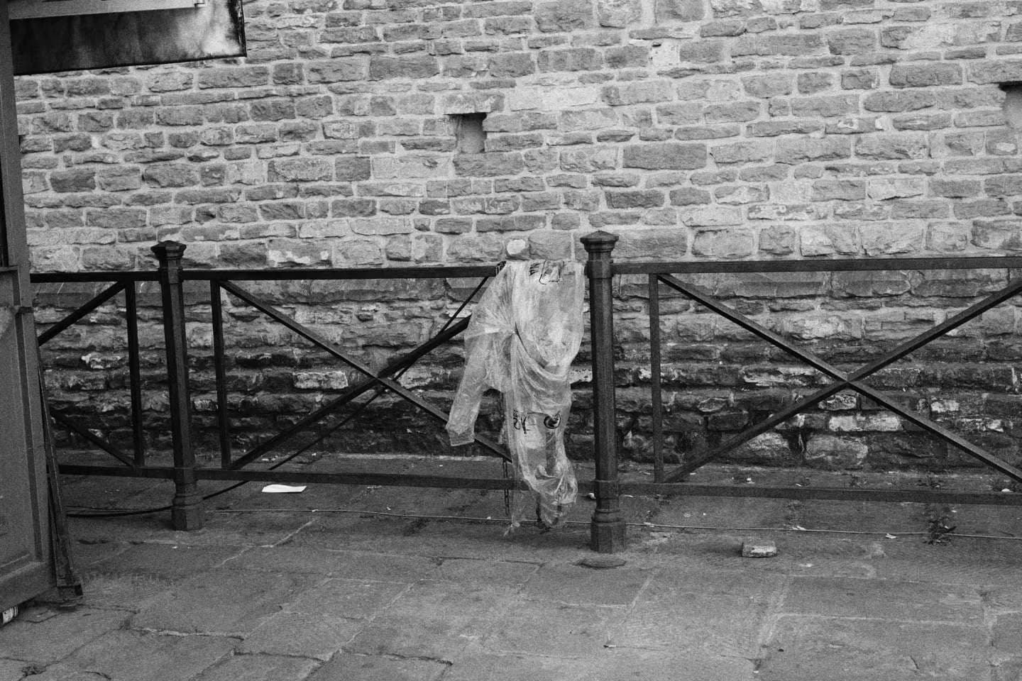 Fabric draped over a railing beside a stone wall.