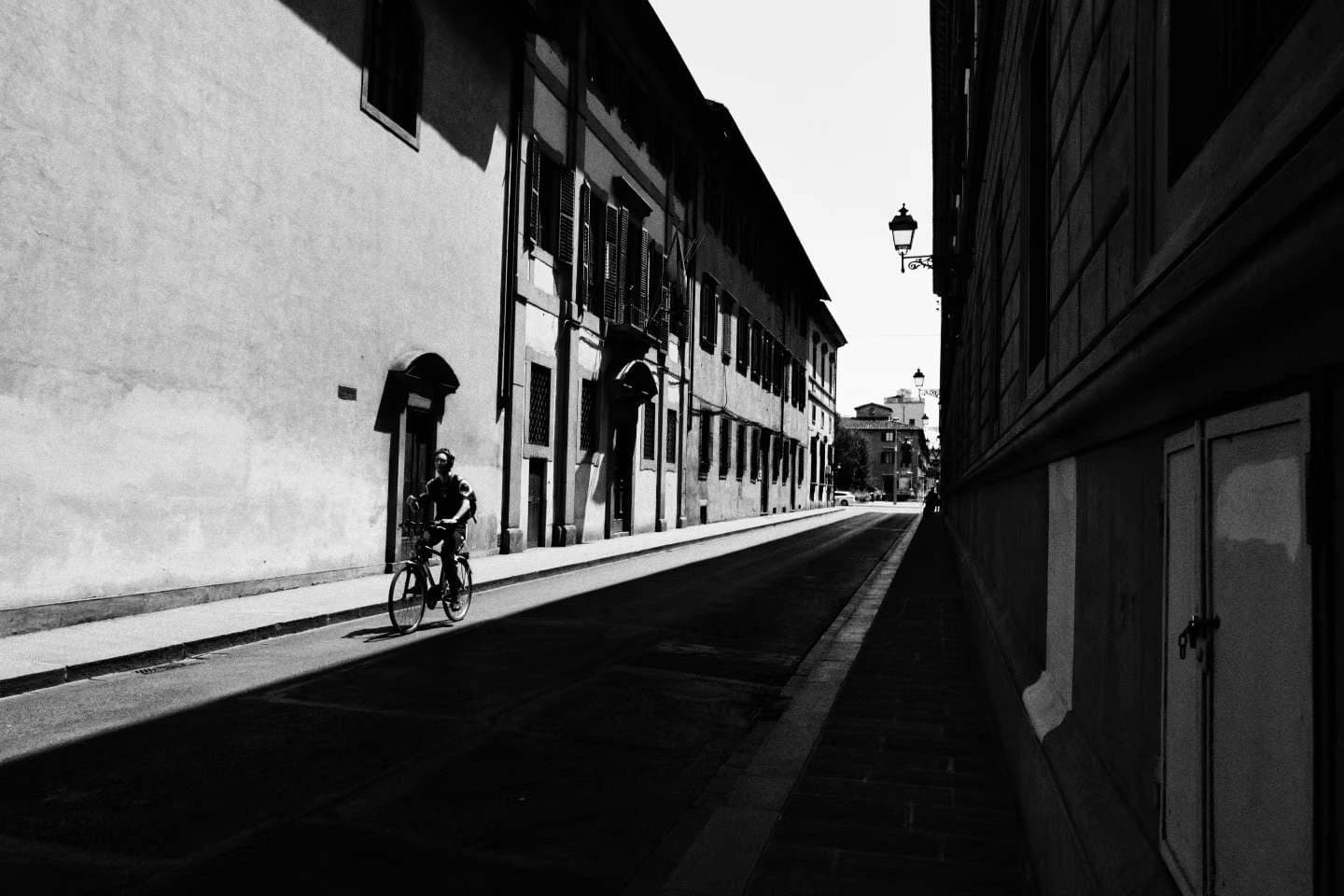 A cyclist crossing a city street, in black and white.