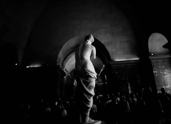 A statue framed by arches.