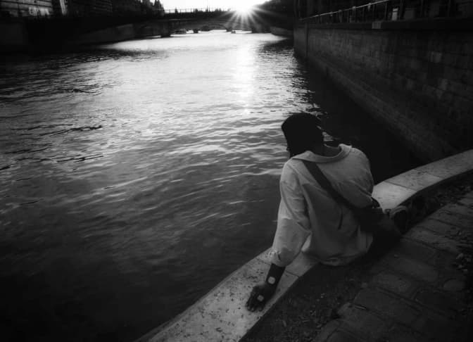 A figure beside a river.
